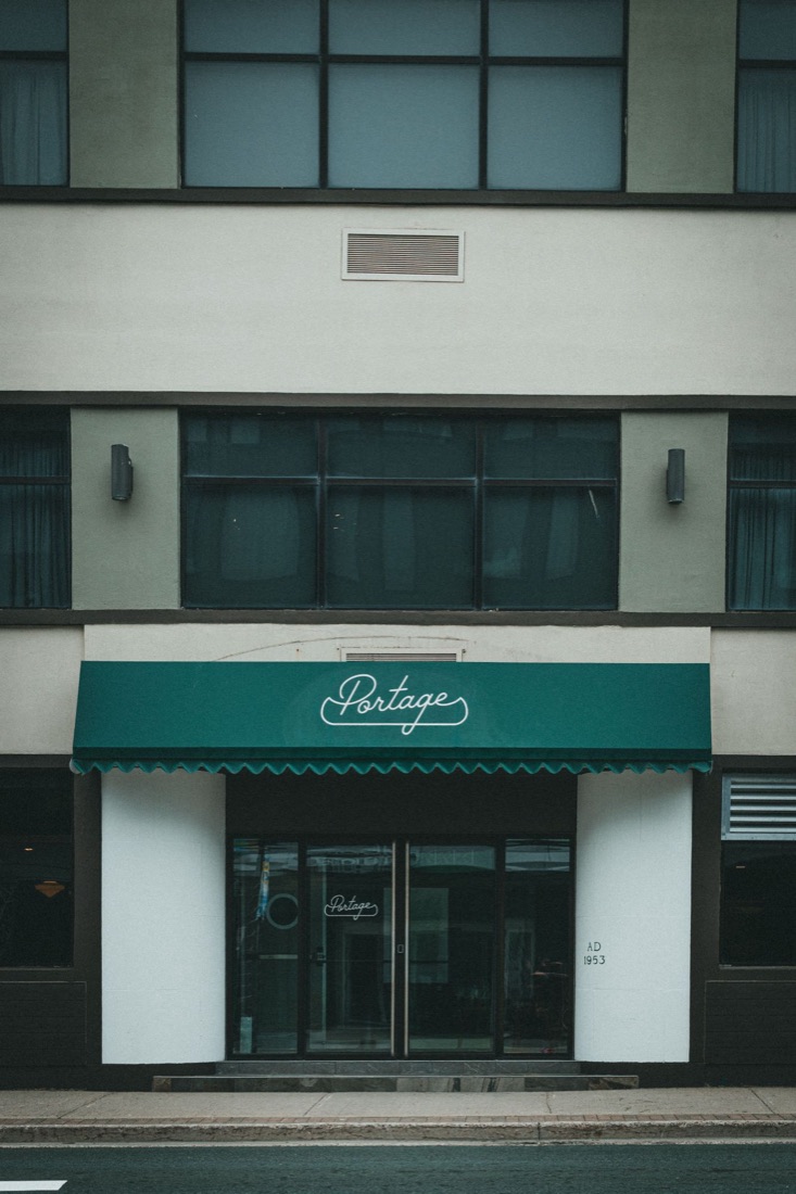 A small storefront with a green awning on a city street