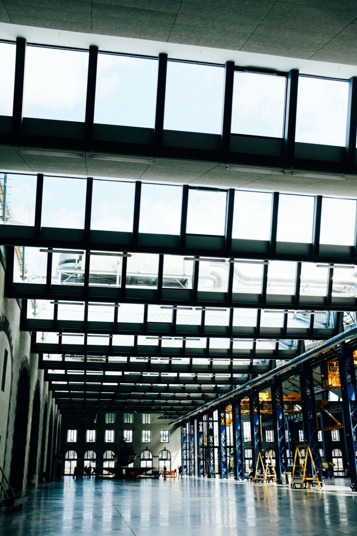 A long, skylit industrial hall with blue steel columns