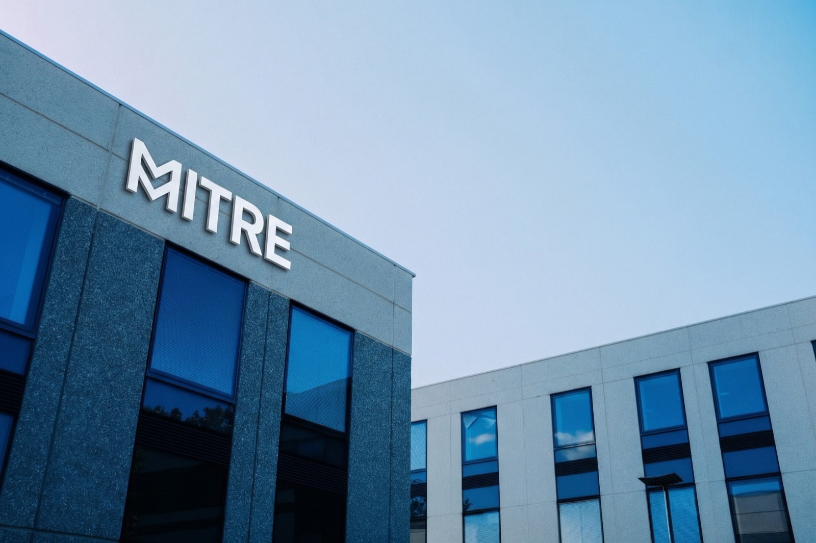 The Mitre logo on the front of an office building against a blue sky